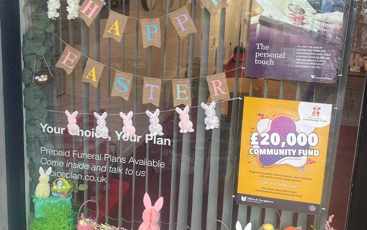 Easter window display with Happy Easter bunting and pink and green bunny decorations.